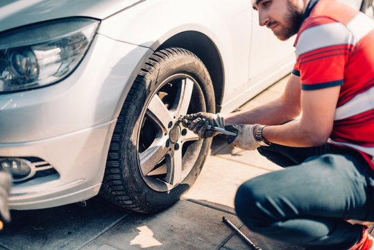 Tire maintenance, damaged car tyre or changing seasonal tires using wrench. Changing a flat car tire on the sideroad or in the courtyard