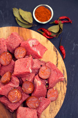 raw meat with smoked sausage on wooden board