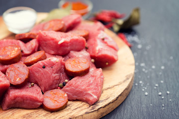 raw meat with smoked sausage on wooden board