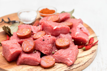 raw meat with smoked sausage on wooden board