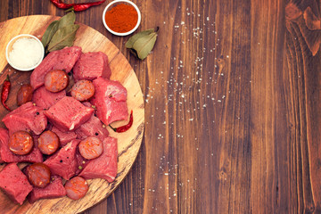 raw meat with smoked sausage on wooden board