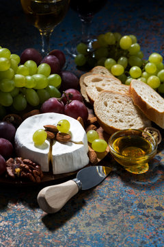 snacks, fruit and Camembert cheese on a dark background, vertical