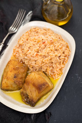 fried cod fish with rice on dish on black ceramic background