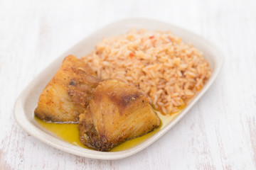 fried cod fish with rice on dish on wooden background