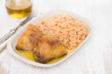 fried cod fish with rice on dish on wooden background