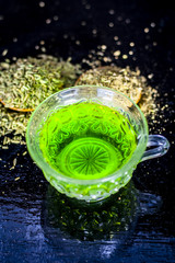 Closes up of essential tea of raw fresh fennel seeds with raw fennel seeds in a transparent cup on wooden surface for good skin and inhibits muscles spasms and helps for a good digestion.