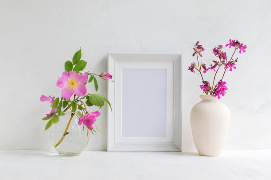 Mockup with a white frame and pink rose hips flowers