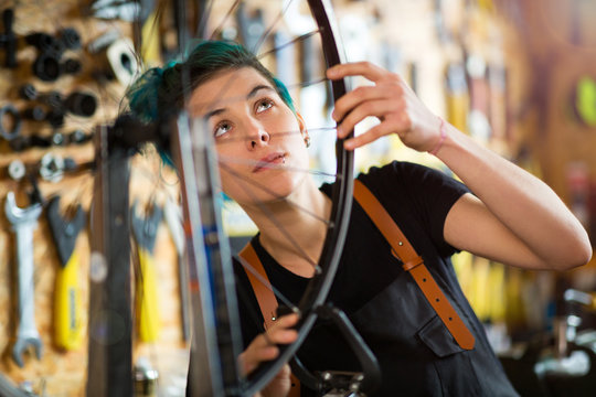 Confident young woman working in a bicycle repair shop
