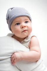 Funny baby in a cap on a light background. Handsome little boy with blue eyes.