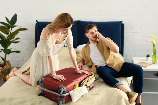 girlfriend and boyfriend packing travel bag for vacation in bedroom