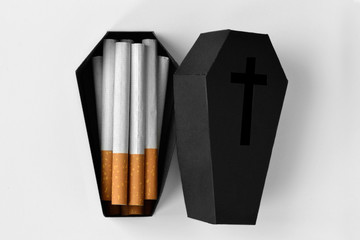 Cigarettes in a black coffin on white background - Stop smoking concept - obrazy, fototapety, plakaty