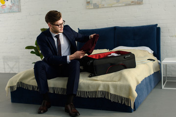 handsome businessman in suit packing bag for business trip