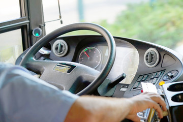 Hands of driver in a modern bus by driving.Concept - close-up of bus driver steering wheel and...