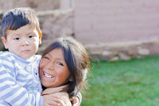 Two latin siblings hugging outside.