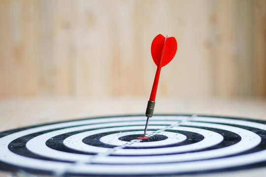 Red dart arrow hit the center target of dartboard metaphor marketing competition concept