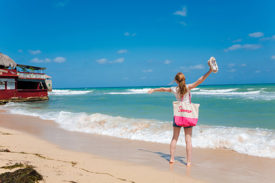 Eine junge Frau spaziert am Strand in der Karibik auf Jamaika