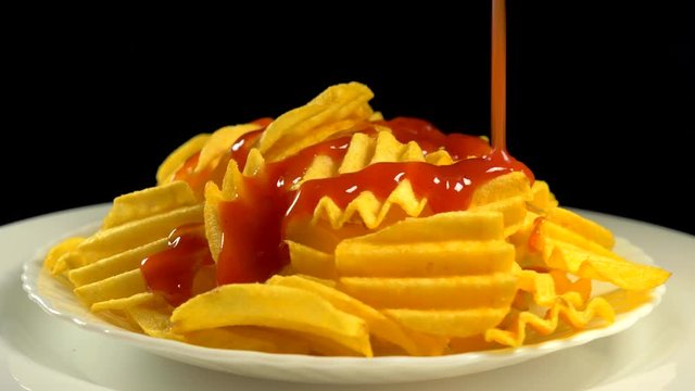 Chips are watered with ketchup on a plate