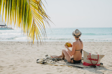 Eine junge Frau sitzt am Strand in der Karibik