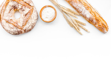 Appetizing fresh bread concept. Baguette and round loaf near ears of wheat on white background top...