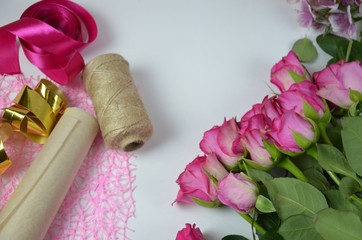 Florist at work: pretty woman making summer bouquet of roses on a working table. Kraft paper, scissors, envelope for congratulations on the table. View from above. Flat lay composition. flower shop