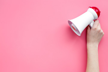 Attract attention concept. Megaphone in hand on pink background top view copy space