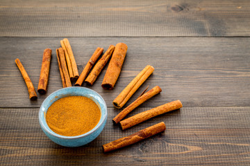 Cinnamon seasoning. Sticks and powder on dark wooden background copy space