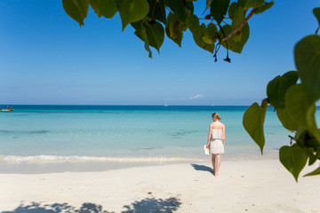 Eine junge Frau spaziert am Strand in der Karibik auf Jamaika
