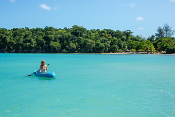 Eine junge Frau paddelt in einem Kajak auf dem Meer in der Karibik auf Jamaika
