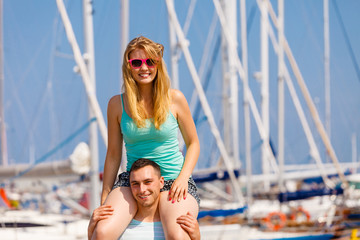 Man giving girlfriend piggyback ride on marina