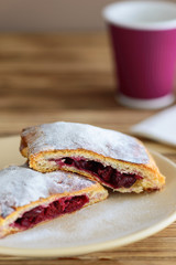slices of strudel from puff pastry with a cup of tea on a wooden table
