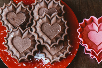 Appetizing chocolate cupcakes in the form of hearts lie on a plate next to silicone forms, the concept of declaration of love