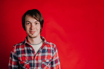 Fototapeta premium Portrait of a man in a plaid shirt on a red background, the man smiles at the camera, copy space