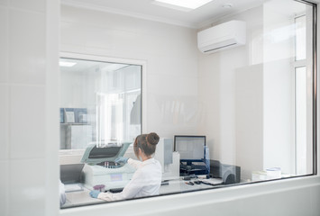View through the glass on the laboratory with medic doing analysis