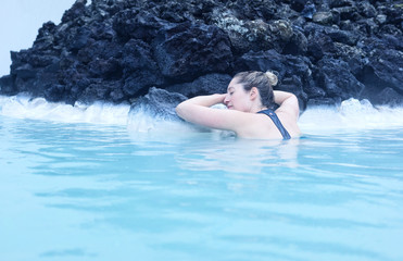 Woman leaning on rocks asleep in a hot spring 