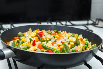 Fresh vegetables in a frying pan. Fresh vegetable products, freshly frozen odietic vegetables, corn, asparagus, pepper, carrots are cooked in a frying pan on a gas stove.