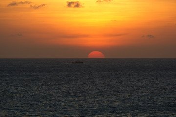 Fototapeta premium Sunset with a semi circle orange sun over the sea