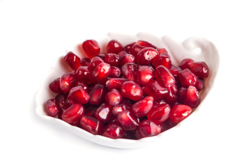 pomegranate seeds on the little plate isolated on white background