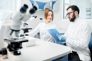 Medics in uniform working with microscope making analysis at the laboratory office