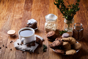 Obraz na płótnie Canvas Coffee cup, jar with coffee beans, cookies over rustic background, selective focus, close-up, top view