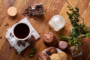 Coffee cup, jar with coffee beans, cookies over rustic background, selective focus, close-up, top view