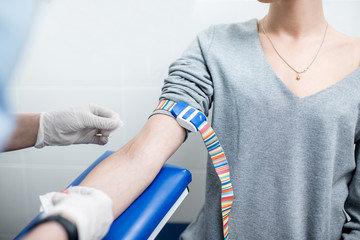Laboratory assistant taking blood with vacuum capsule for test from the arm vein in the laboratory
