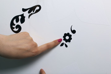 The girl glues the cut out elements from self-adhesive paper, to mask the defects of the white door.