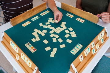 Turkish board game Okey (Rummikub). A table with green cloth and chips. Hands of the players.