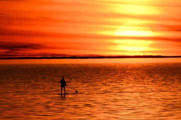 Fototapeta na wymiar Paddle Boarder at Sunset on Bay