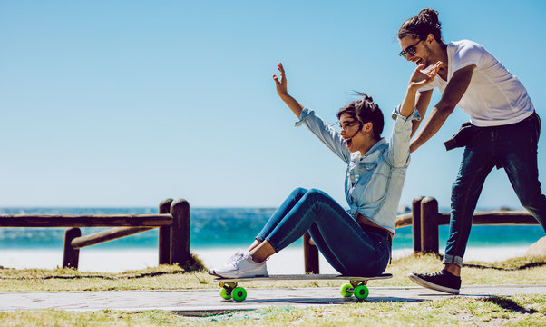 Loving couple playing on skateboard near the beach - Powered by Adobe