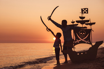 Father and son  playing on the beach at the sunset time.