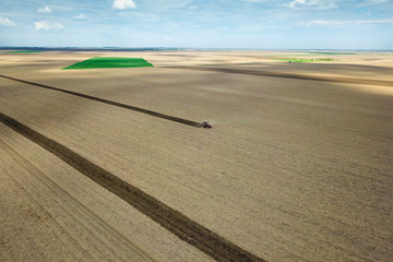 Red tractor plow the field Air view