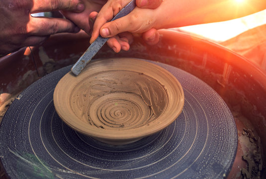 hand maid, molding from clay, making dishes at sunset.