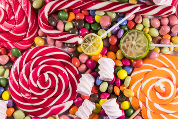 Background of colorful chocolate candies, lollipops, candy cane and marshmallows