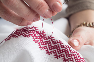 Woman's hands embroider ornaments